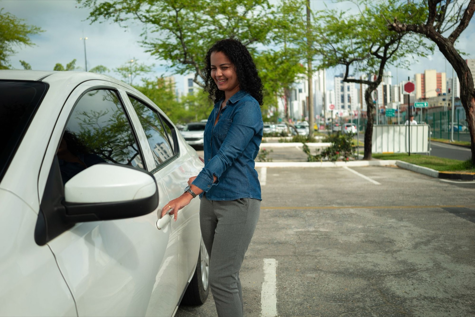 A smiling driver opening her car door in a car park